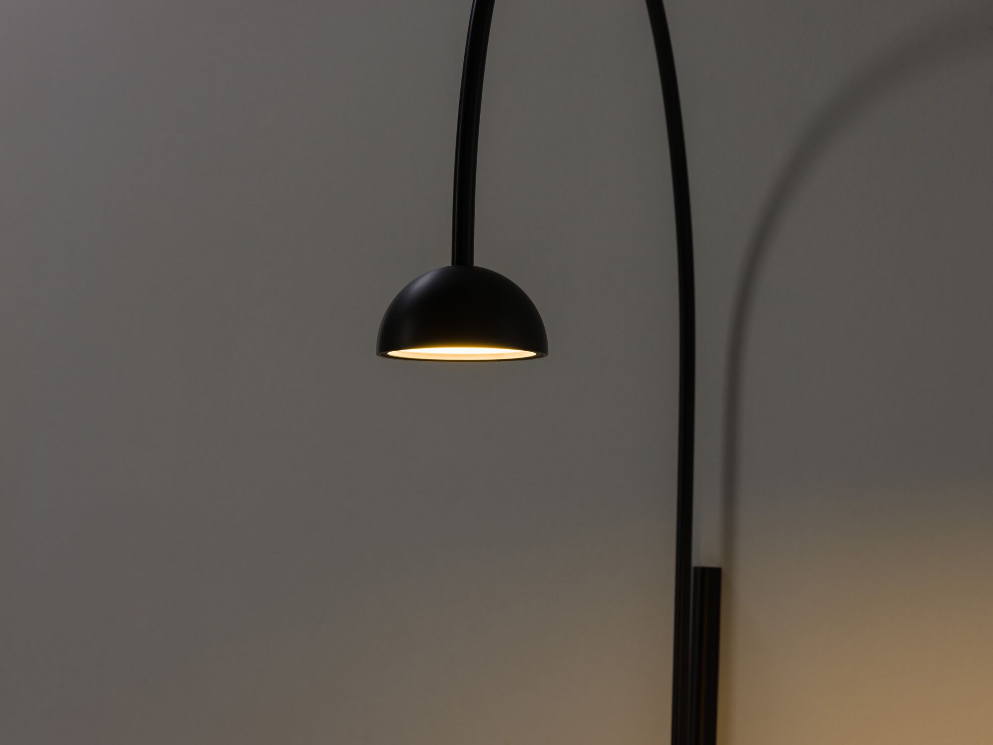 Black arched wall lamp with light on detail view